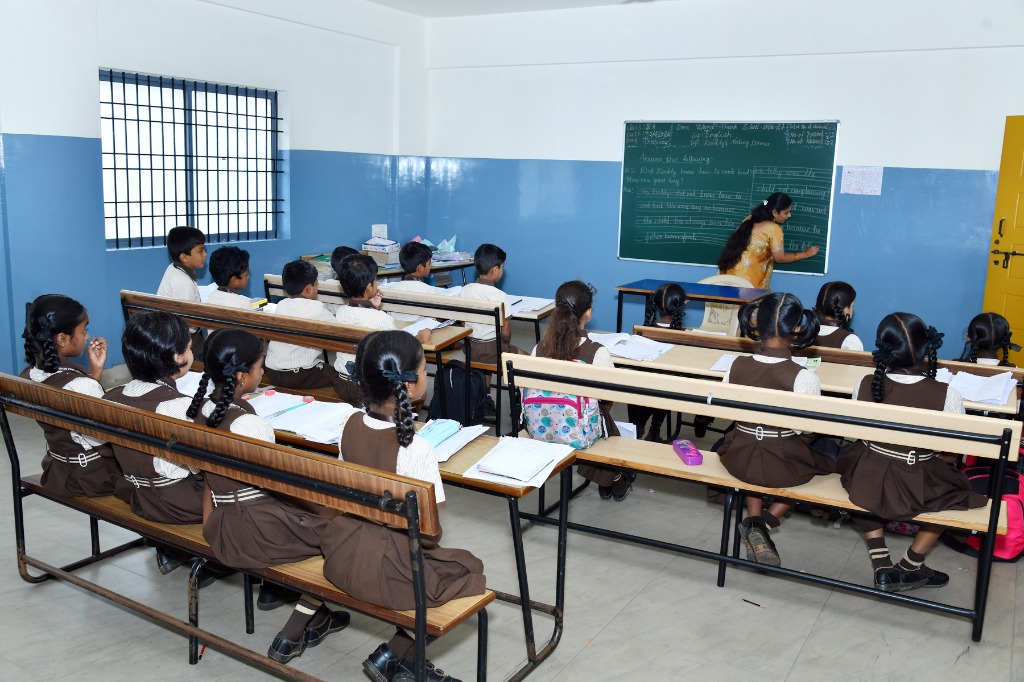 Teacher explaining English lesson writing on blackboard in classroom