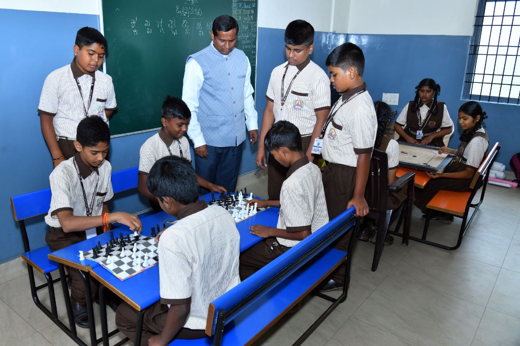Students playing chess and carrom indoor board games inside classroom